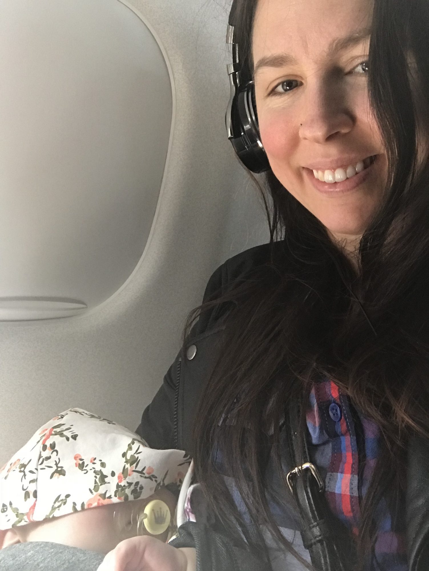 mom holding baby on the window seat of the plane