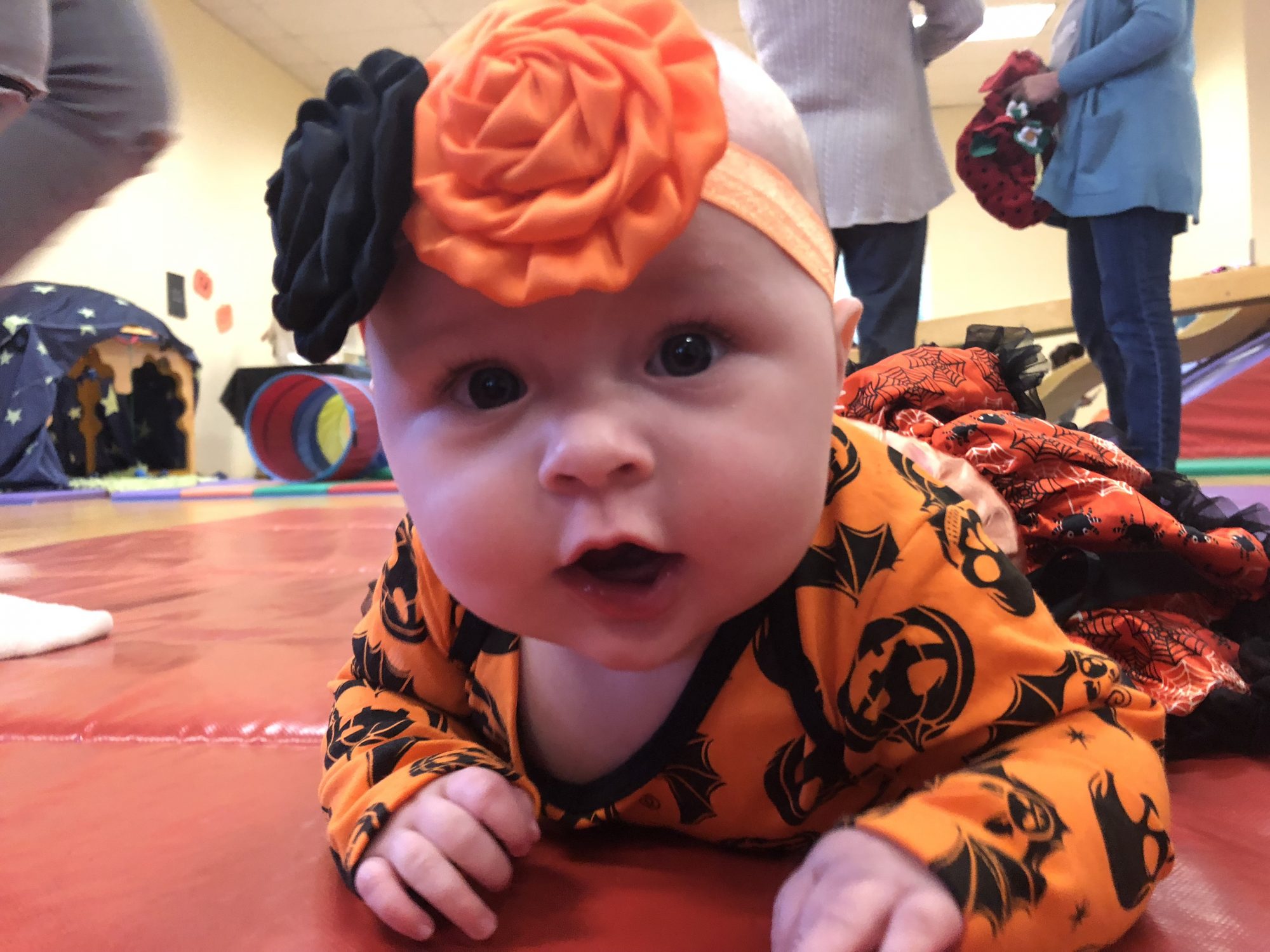baby in Halloween clothing crawling on the mat at a baby gym